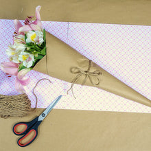 a bouquet of flowers wrapped in brown paper next to a pair of scissors